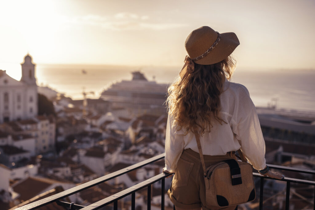 Woman enjoying a solo adventure at sunset overlooking a coastal European city — symbolic of self-connection, feminine freedom, and inner clarity.